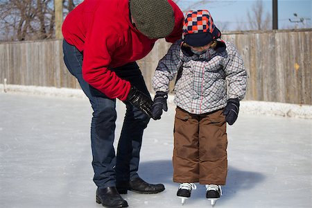 simsearch:400-08034847,k - Father teaching son how to ice skate at an outdoor skating rink in winter. Photographie de stock - Aubaine LD & Abonnement, Code: 400-06564245