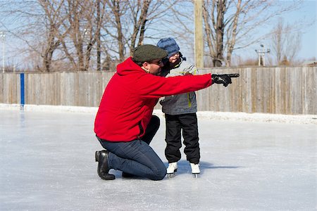 Father teaching daughter how to ice skate at an outdoor skating rink in winter. Photographie de stock - Aubaine LD & Abonnement, Code: 400-06564242