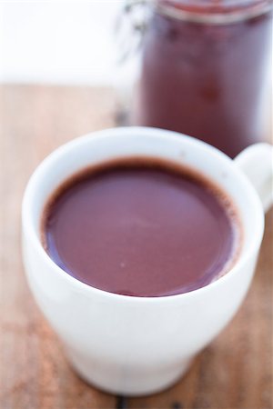 simsearch:400-08338402,k - Closeup of cup of hot chocolate on a wooden table with cocoa powder in glass jar in background Foto de stock - Super Valor sin royalties y Suscripción, Código: 400-06565007