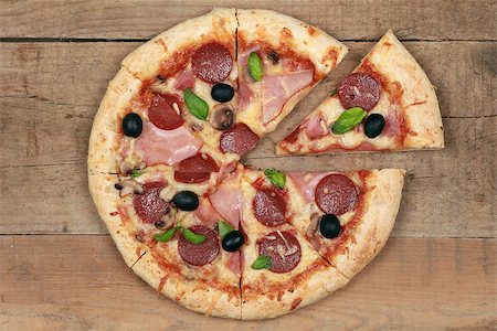 sliced mushroom - Sliced Deluxe Pizza with cheese, ham, pepperoni, mushrooms and olives on a wooden table Foto de stock - Super Valor sin royalties y Suscripción, Código: 400-06567540