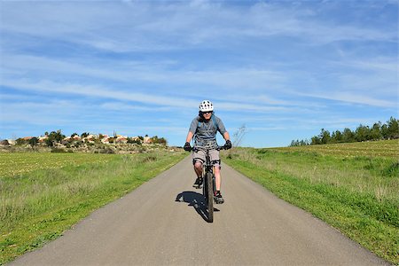 Forest, field, village and mountain biker on a road. Stock Photo - Budget Royalty-Free & Subscription, Code: 400-06561897