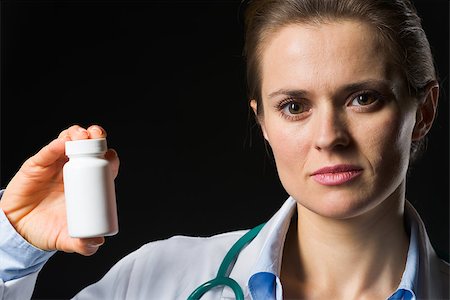 simsearch:400-05092596,k - Medical doctor woman showing medicine bottle on black background Stock Photo - Budget Royalty-Free & Subscription, Code: 400-06562772