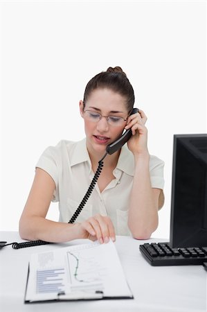Portrait of a businesswoman making a phone call while looking at a document against a white background Stock Photo - Budget Royalty-Free & Subscription, Code: 400-06627021