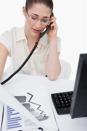 Portrait of a secretary making a phone call while looking at statistics against a white background Stock Photo - Budget Royalty-Free & Subscription, Code: 400-06627022