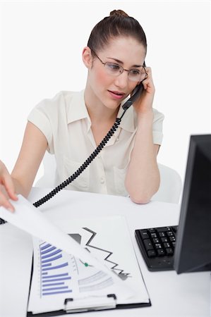 Portrait of a saleswoman making a phone call while looking at statistics against a white background Stock Photo - Budget Royalty-Free & Subscription, Code: 400-06627023