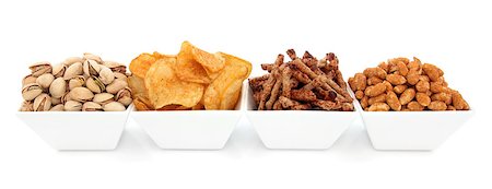 simsearch:400-07994208,k - Pistachio nuts, potato crisps, twiglet and roasted peanut savoury snacks in porcelain dishes over white background. Photographie de stock - Aubaine LD & Abonnement, Code: 400-06629618