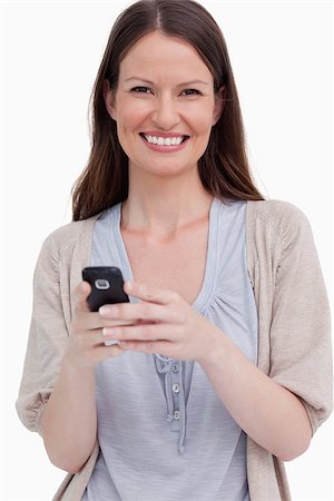 simsearch:400-05751258,k - Close up of smiling woman with her cellphone against a white background Stock Photo - Budget Royalty-Free & Subscription, Code: 400-06634516