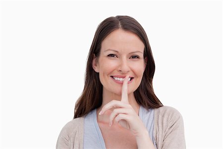 simsearch:6109-06194921,k - Close up of smiling woman asking for silence against a white background Stock Photo - Budget Royalty-Free & Subscription, Code: 400-06634521