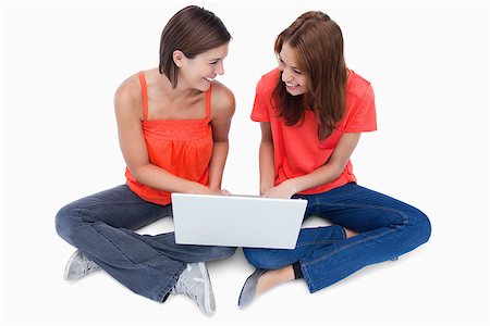 simsearch:400-06634629,k - Smiling teenagers sitting with legs crossed and a laptop on them Fotografie stock - Microstock e Abbonamento, Codice: 400-06634646