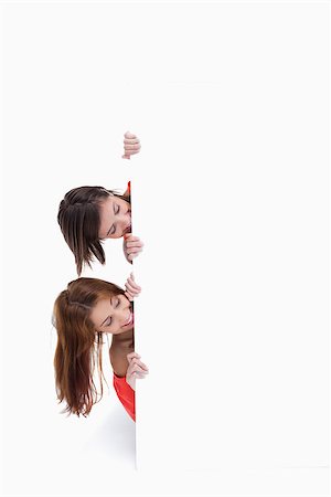 simsearch:400-06634629,k - Teenagers showing their heads on the side of a blank poster Fotografie stock - Microstock e Abbonamento, Codice: 400-06634643