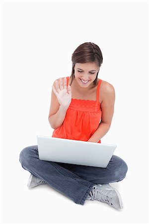 Teenage beaming while sitting cross-legged and saying hello to her laptop Stock Photo - Budget Royalty-Free & Subscription, Code: 400-06634659