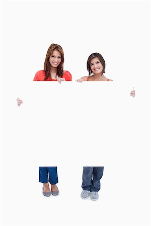 simsearch:400-06634629,k - Two smiling teenagers holding a blank poster against a colourless background Fotografie stock - Microstock e Abbonamento, Codice: 400-06634874