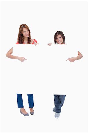 simsearch:400-06634629,k - Smiling teenagers showing the blank poster while pointing their fingers on it Fotografie stock - Microstock e Abbonamento, Codice: 400-06634876