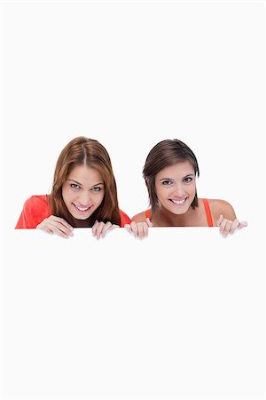 simsearch:400-06634629,k - Smiling teenagers holding a blank poster while hiding behind it Fotografie stock - Microstock e Abbonamento, Codice: 400-06634879