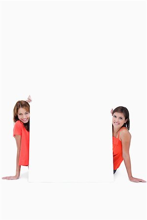 simsearch:400-06634629,k - Two teenagers smiling while sitting behind a blank poster Fotografie stock - Microstock e Abbonamento, Codice: 400-06634880