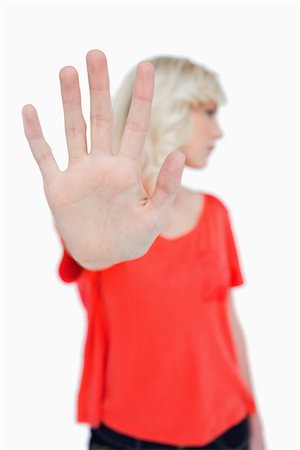 simsearch:400-06635276,k - Stop hand gesture made by a young blonde woman against a white background Photographie de stock - Aubaine LD & Abonnement, Code: 400-06635277