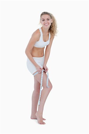 Smiling young blonde woman measuring her thigh against a white background Stock Photo - Budget Royalty-Free & Subscription, Code: 400-06635286