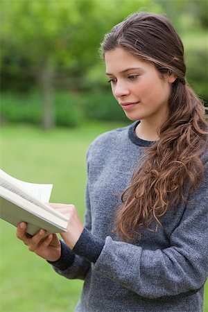 simsearch:400-03923096,k - Young relaxed woman reading a book while standing upright in the countryside Stock Photo - Budget Royalty-Free & Subscription, Code: 400-06635329