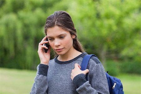 Young calm girl using her cellphone while carrying her backpack Stock Photo - Budget Royalty-Free & Subscription, Code: 400-06635375