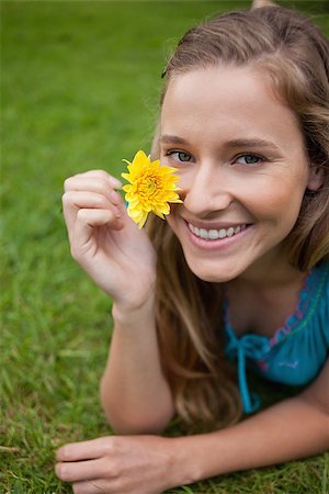 Smiling young girl showing a beautiful yellow flower while lying on the grass in a park Stock Photo - Budget Royalty-Free & Subscription, Code: 400-06635418