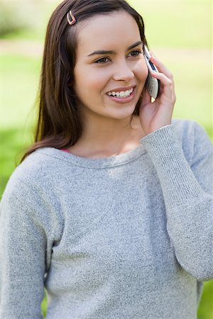 Young girl talking with her cellphone while standing in a parkland Stock Photo - Budget Royalty-Free & Subscription, Code: 400-06635432