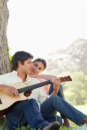 Man looking downwards while playing the guitar as his friend watches him Foto de stock - Super Valor sin royalties y Suscripción, Código: 400-06635933