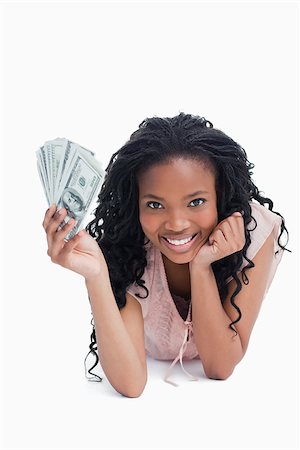 simsearch:400-06636885,k - A young woman holding American dollars is resting her head on her hand against a white background Photographie de stock - Aubaine LD & Abonnement, Code: 400-06636850