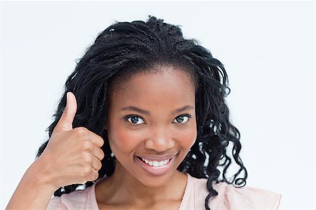 simsearch:400-06636885,k - A young woman who is smiling at the camera with her thumb up against a white background Photographie de stock - Aubaine LD & Abonnement, Code: 400-06636868