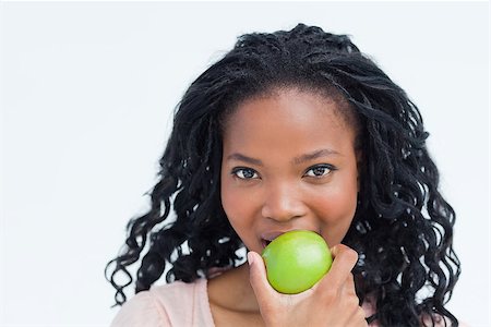 simsearch:400-06636885,k - A head shot of a young woman who is eating a green apple Photographie de stock - Aubaine LD & Abonnement, Code: 400-06636961