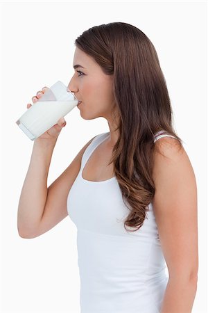 Side view of a young woman drinking a glass of milk against a white background Stock Photo - Budget Royalty-Free & Subscription, Code: 400-06637453