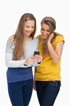 Two females student smiling while looking a cellphone against white background Stock Photo - Budget Royalty-Free & Subscription, Code: 400-06637930