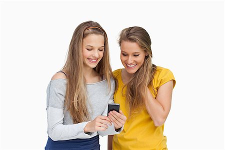 Two smiling students looking a cellphone screen against white background Stock Photo - Budget Royalty-Free & Subscription, Code: 400-06637933