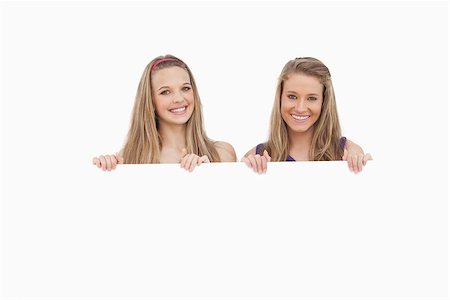 Close-up of two young women holding a blank sign against white background Stock Photo - Budget Royalty-Free & Subscription, Code: 400-06638086