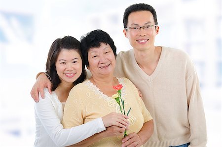 Asian family at home. Adult offsprings giving carnation flowers to senior mother. Stock Photo - Budget Royalty-Free & Subscription, Code: 400-06639655
