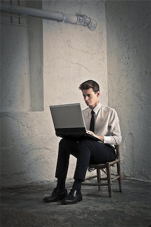 Young man using a laptop sitting in a basement Stockbilder - Microstock & Abonnement, Bildnummer: 400-06639907