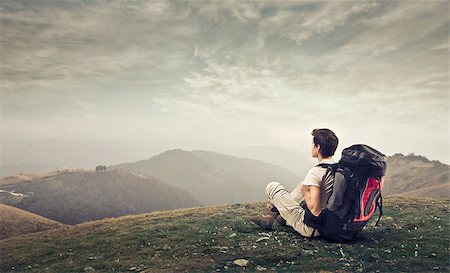 Boy sitting with his travel backpack on a hill Stock Photo - Budget Royalty-Free & Subscription, Code: 400-06639940