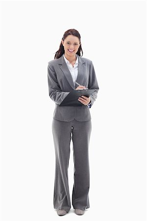 reports white background - Businesswoman smiling while writing on a clipboard against white background Stock Photo - Budget Royalty-Free & Subscription, Code: 400-06632207