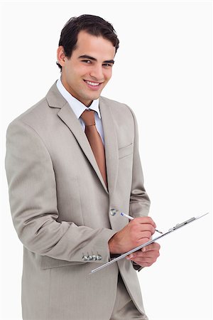 simsearch:400-06633122,k - Smiling salesman with notepad and pen against a white background Stock Photo - Budget Royalty-Free & Subscription, Code: 400-06633375