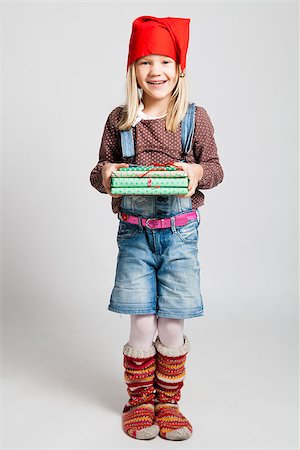 Studio portrait of happy smiling young girl with red Christmas hat and woollen socks holding Christmas gifts Photographie de stock - Aubaine LD & Abonnement, Code: 400-06633600