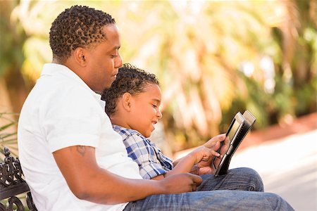 Happy African American Father and Mixed Race Son Having Fun Using Touch Pad Computer Tablet Outside. Stock Photo - Budget Royalty-Free & Subscription, Code: 400-06633884
