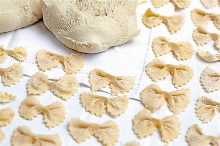 Raw handmade pasta in shape of bow tie over a white table cloth. Traditional italian cuisine. Foto de stock - Super Valor sin royalties y Suscripción, Código: 400-06642180