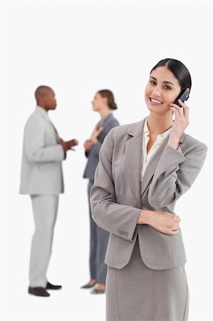 simsearch:400-06686562,k - Smiling saleswoman with cellphone and colleagues behind her against a white background Foto de stock - Super Valor sin royalties y Suscripción, Código: 400-06685316