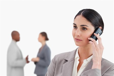 simsearch:400-06686555,k - Saleswoman with cellphone and colleagues behind her against a white background Stock Photo - Budget Royalty-Free & Subscription, Code: 400-06685317