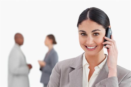 simsearch:400-06686562,k - Smiling businesswoman with mobile phone and colleagues behind her against a white background Foto de stock - Super Valor sin royalties y Suscripción, Código: 400-06685319
