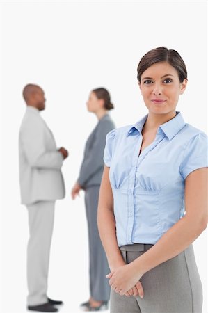 simsearch:6109-06002735,k - Saleswoman with talking associates behind her against a white background Stock Photo - Budget Royalty-Free & Subscription, Code: 400-06685343