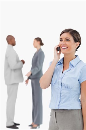 simsearch:400-06686555,k - Smiling saleswoman on the phone with colleagues behind her against a white background Stock Photo - Budget Royalty-Free & Subscription, Code: 400-06685354