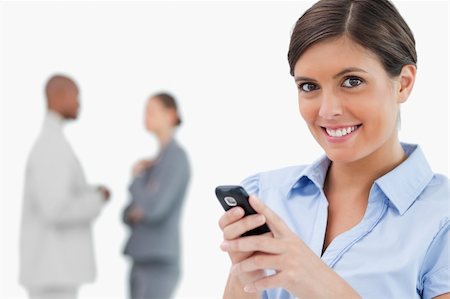 simsearch:400-06686562,k - Smiling saleswoman holding mobile phone with colleagues behind her against a white background Foto de stock - Super Valor sin royalties y Suscripción, Código: 400-06685350