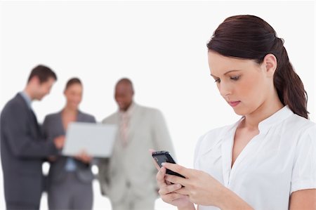 simsearch:400-06686555,k - Saleswoman reading text message with colleagues behind her against a white background Stock Photo - Budget Royalty-Free & Subscription, Code: 400-06685386