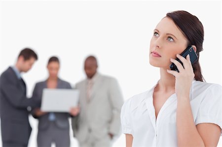 simsearch:400-06686562,k - Businesswoman listening to caller with colleagues behind her against a white background Foto de stock - Super Valor sin royalties y Suscripción, Código: 400-06685382