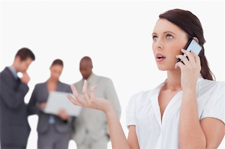 simsearch:400-06686562,k - Saleswoman talking on the phone with colleagues behind her against a white background Foto de stock - Super Valor sin royalties y Suscripción, Código: 400-06685383